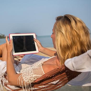 Young woman smiling and holding phone she uses to back up her video collection to the cloud so she has room for apps and music.